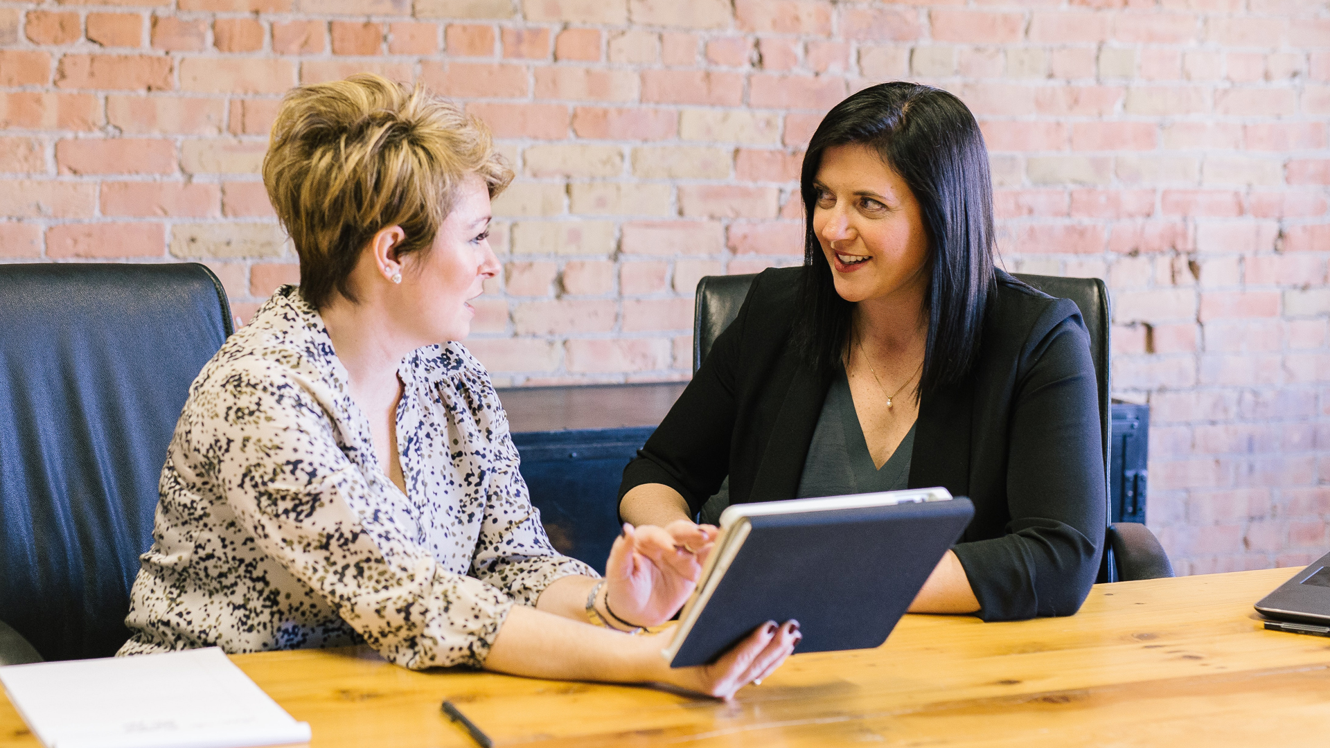 Two women sat at a desk looking at a tablet device