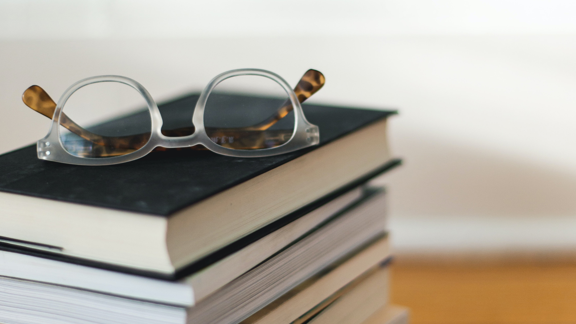 Close up of a pair of glasses on top of a pile of books