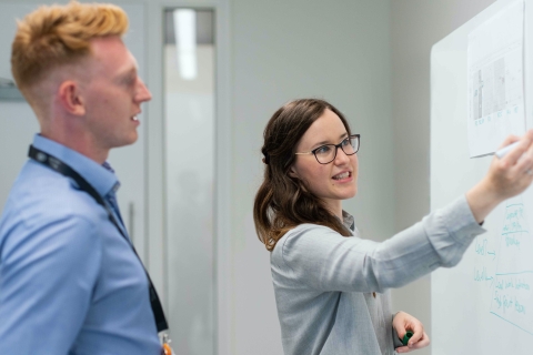 Man and a woman writing on a white board